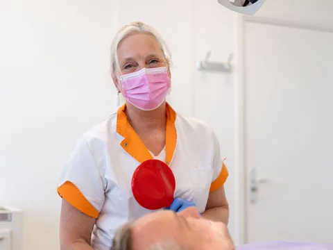 Tandartsassistent Caroline bij een patiënt in de behandelstoel