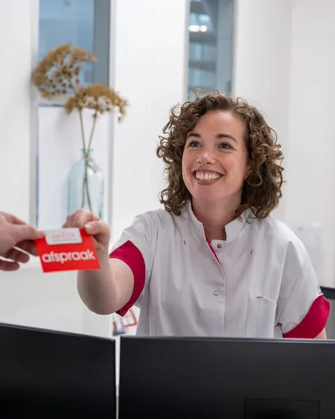 Medewerker van de receptie geeft een afspraakkaartje mee