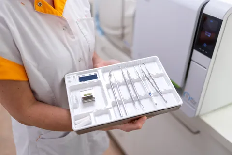 Een collega houdt een bakje met instrumenten voor het mondonderzoek vast, waaronder sondes om het tandvlees te meten