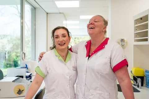 Twee collega's staan lachend naast elkaar