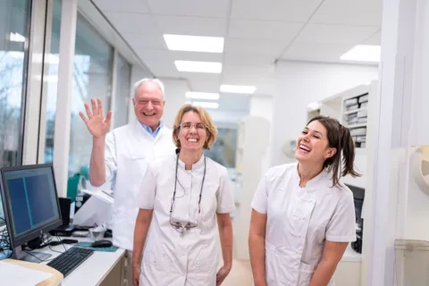 Drie zorgverleners van ons team lachen en zwaaien in de praktijk