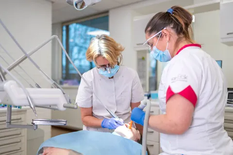 Tandarts vergelijkt de kleur van de witte vulling met de tand van een patiënt